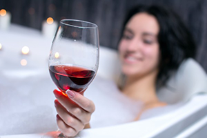 Женщина в ванной с бокалом вина