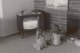 Дети смотрят телевизор, сидя на полу